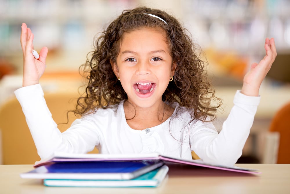 Excited school girl at the library looking surprised